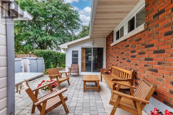 Backyard patio with wooden chairs and tables, adjacent to the brick exterior of the house. - 5159 Shirley Avenue, Niagara Falls