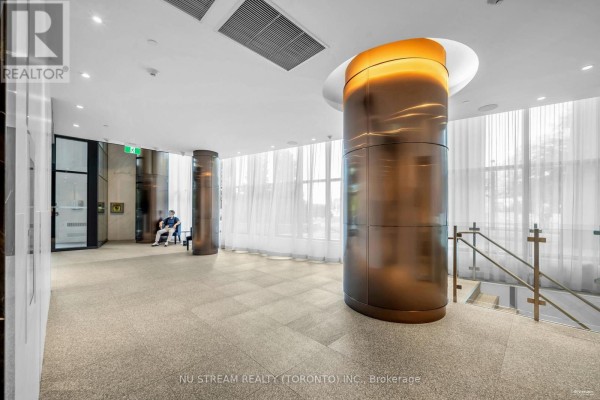 The building lobby featuring a large bronze-wrapped column, textured floor, and sheer curtains. - 516 - 585 Bloor Street E, Toronto