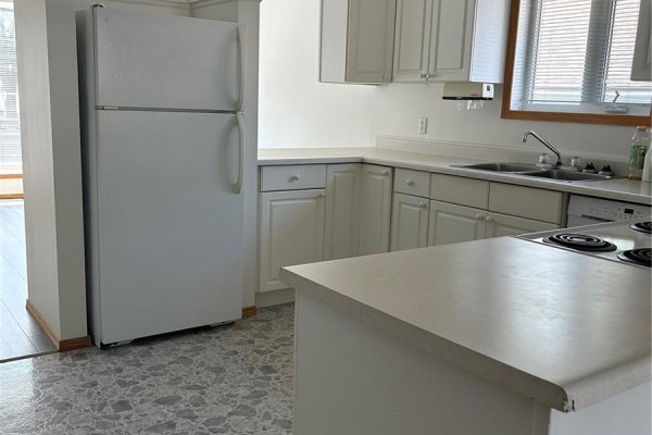 Kitchen with white appliances, including a refrigerator, and white cabinetry. - 516-518 Centre Street, Shaunavon