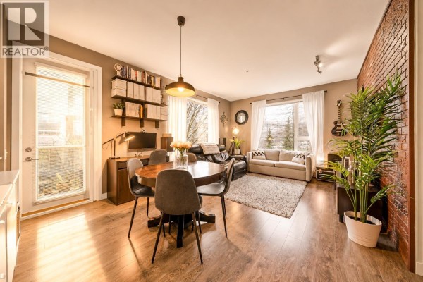 Dining area with round table, chairs, and access to a balcony through sliding glass doors. - 516 9250 University High Street, Burnaby