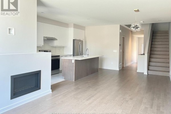 Living area with fireplace, open-concept kitchen, and staircase leading upstairs. - 516 Borbridge Avenue, Ottawa