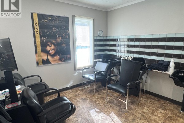 Waiting area with black chairs, hair washing station, and decorative poster. - 516 La Ronge Avenue, La Ronge
