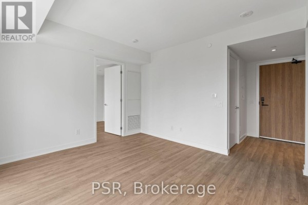Empty apartment living space with light wood floors, white walls, and doorways leading to other rooms. - 517 - 299 Campbell Avenue, Toronto