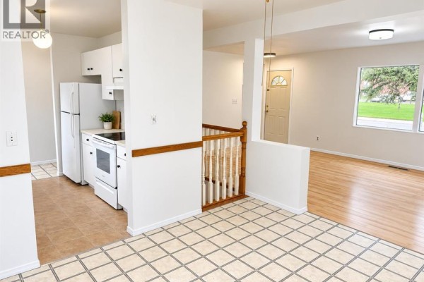 Living room with light wood floors, blue sofas, a coffee table, and a large window. - 517 55 Avenue W, Claresholm