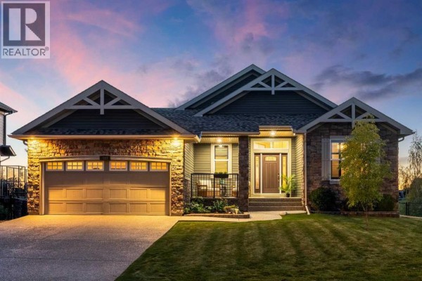 A residential house with stone accents, a large garage door, and a covered front porch. - 517 Boulder Creek Circle Se, Langdon