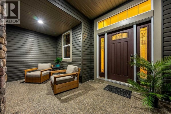 Front door entrance with a covered porch, two chairs, and stained glass sidelights. - 517 Boulder Creek Circle Se, Langdon