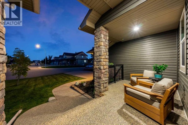 View from the covered front porch showing outdoor seating and the street in front of the house. - 517 Boulder Creek Circle Se, Langdon