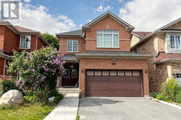 Close-up of the house exterior showcasing red brick, brown garage door, and white-trimmed windows. - 517 Navigator Drive, Mississauga