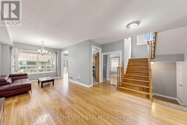 Interior living room with hardwood floors, a leather sofa, coffee table, and wooden staircase. - 517 Navigator Drive, Mississauga