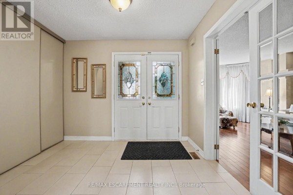 Foyer with beige tiled floor, white double doors with stained glass, and double doors to living room. - 5172 Hidden Valley Court, Mississauga