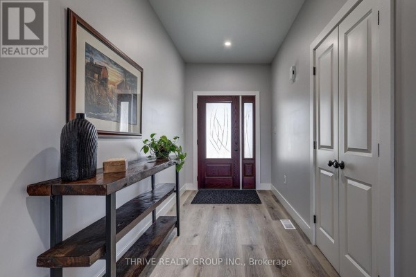 Interior front hallway with wood-look flooring and a dark wood door. - 5178 Glendon Drive, Southwest Middlesex