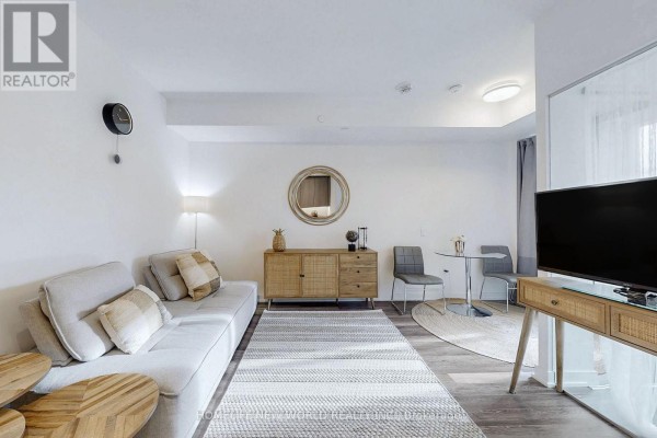 Living room features a sofa, woven sideboard, small dining table, and light wood flooring. - 518 - 250 Lawrence Avenue W, Toronto