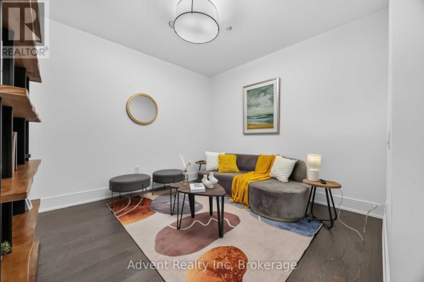 A hallway with white walls, a wooden door, and dark wood floors. - 518 - 30 Inn On The Park Drive, Toronto