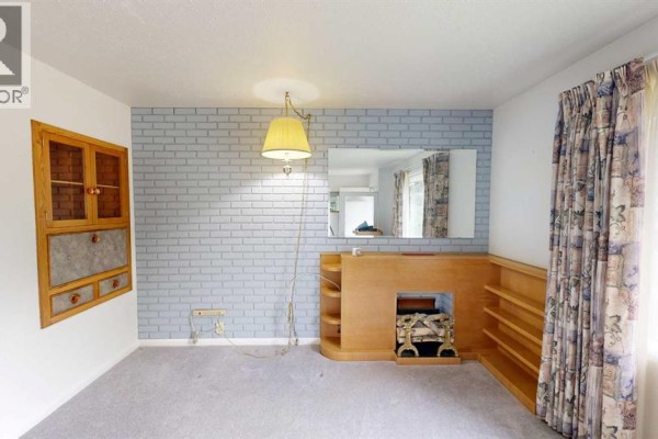 Living room with light blue brick accent wall, fireplace, built-in wooden shelving, and patterned curtains. - 518 11 Street N, Lethbridge
