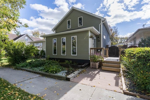 Exterior of a green siding house with a wooden deck and stairs. - 518 Harvard Avenue E, Winnipeg