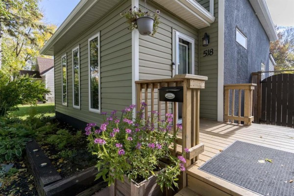 Close-up of the wooden deck and entrance of the green siding house. - 518 Harvard Avenue E, Winnipeg