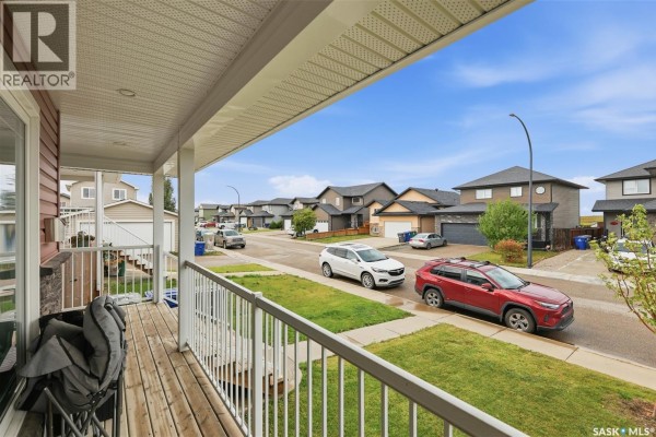 View from the covered porch looking down the street with parked cars and neighboring houses. - 518 Klassen Crescent, Saskatoon