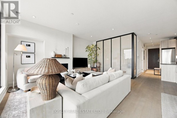 Living room with fireplace, sectional sofa, and a view of a frosted glass partition leading to another room. - 519 - 365 Beech Avenue, Toronto