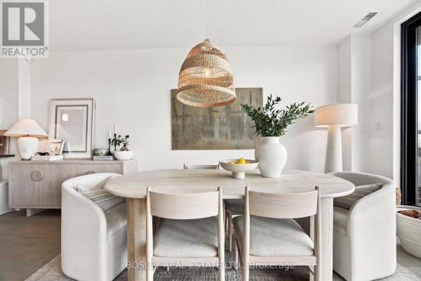 Dining area with a light wood oval table, upholstered chairs, and a large woven pendant light. - 519 - 365 Beech Avenue, Toronto