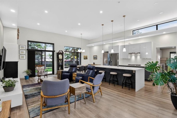 Open-concept living area with kitchen island, blue armchairs, and wood floors. - 519 Cote Avenue, St Pierre Jolys