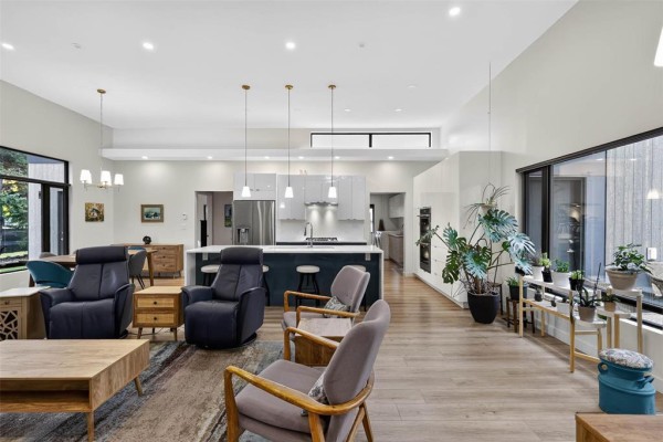 Spacious living area with fireplace, blue recliners, kitchen island, and plants. - 519 Cote Avenue, St Pierre Jolys