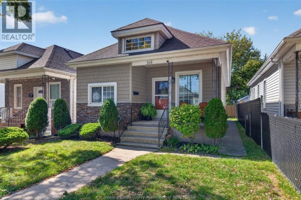 Side view of the tan house with a walkway, green lawn, and neighbor's fence. - 519 Mckay, Windsor