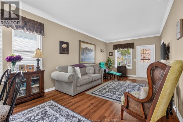 Living room with a sofa, armchair, two rugs, and wooden floors, painted in a neutral color. - 519 Mckay, Windsor