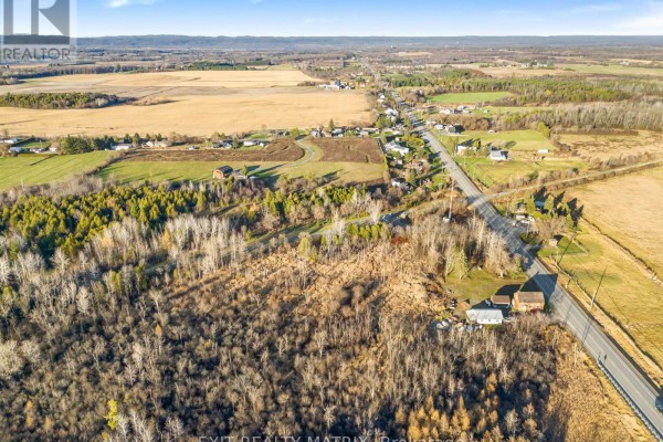 Overhead view of a residential area with scattered houses, trees, and a main road. - 5190 Highway 34, Champlain