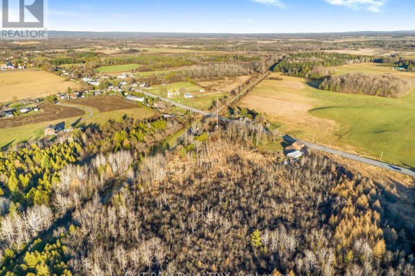 Wide aerial shot showcasing a vast landscape of trees, fields, and a rural road network. - 5190 Highway 34, Champlain