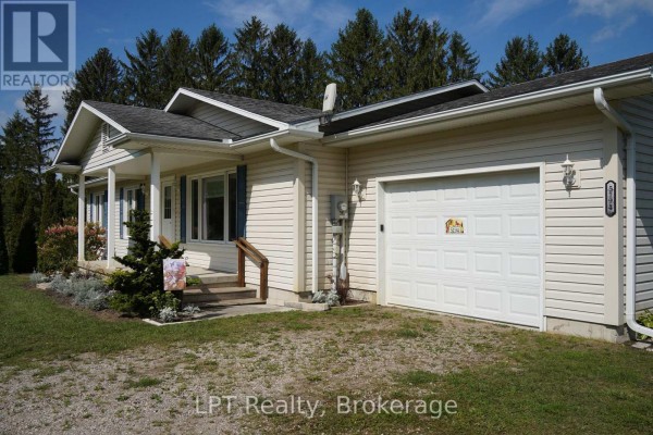 Side view of a light-colored vinyl-sided bungalow with a white garage door and front entrance. - 5194 Bruce Road 3 Road, Saugeen Shores