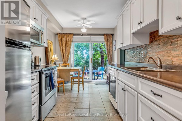 Kitchen with white cabinets, stainless steel appliances, and sliding doors opening to a backyard. - 52 - 16 Hadati Road, Guelph