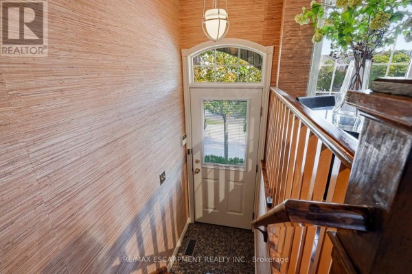 Interior view of a bright entryway with a glass door, wood banister, and textured walls. - 52 - 3480 Upper Middle Road, Burlington