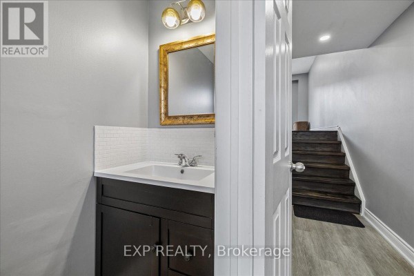 Powder room with a white vanity, gold framed mirror, and dark brown vanity cabinet. - 52 - 371 Bronte Street S, Milton