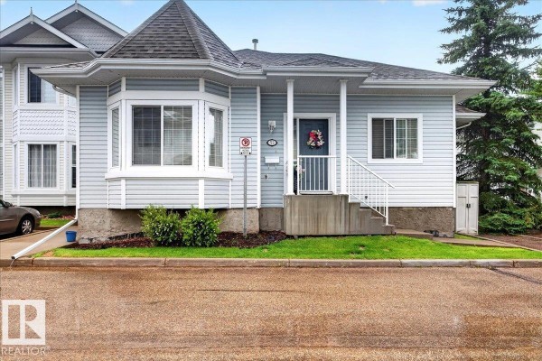 Front exterior of a light blue duplex with white trim, bay window, and a covered porch. - #52 1780 Glastonbury Bv Nw, Edmonton