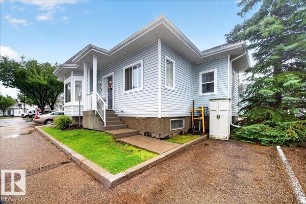Side exterior view of a light blue duplex, showing a bay window and a small white storage shed. - #52 1780 Glastonbury Bv Nw, Edmonton