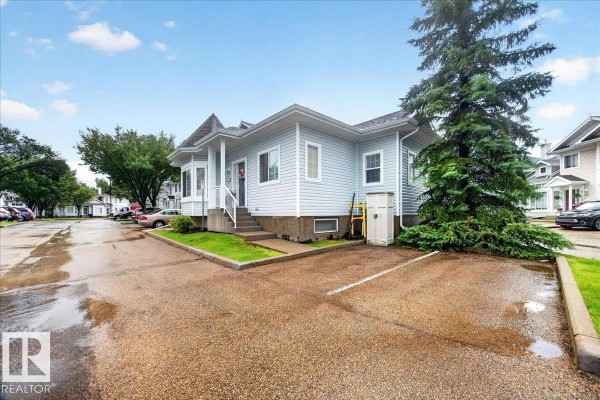 Angled exterior view of a light blue duplex with a bay window and a mature evergreen tree. - #52 1780 Glastonbury Bv Nw, Edmonton