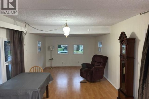 Living room with laminate flooring, a dining table, recliner chair, and multiple windows. - 52 21163 Lougheed Highway, Maple Ridge