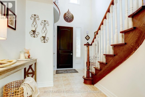 Interior foyer with a dark wood staircase, tiled floor, and a dark wood front door. - 52 Bardoe Crescent, Milton