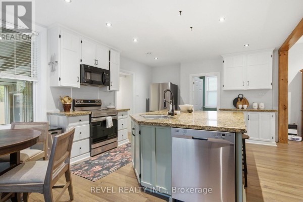 Modern kitchen with island, granite counters, stainless steel appliances, and dining area - 52 Cambridge Street N Kawartha Lakes