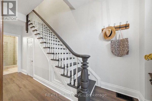 Renovated staircase with white spindles and dark treads, wooden floor, hat rack - 52 Cambridge Street N Kawartha Lakes
