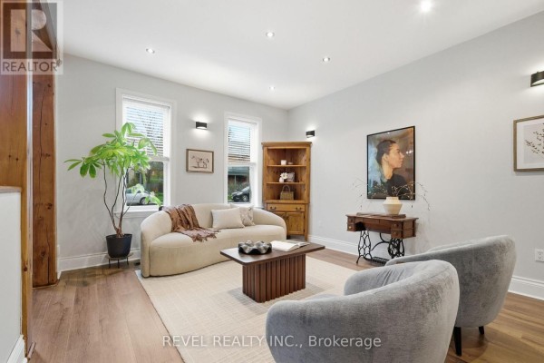 Living room furnished with a sofa, two chairs, a wooden cabinet, and a vintage sewing machine table. - 52 Cambridge Street N, Kawartha Lakes