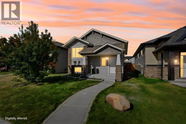 Front exterior of a two-story house at dusk with warm lighting and orange sky. - 52 Castella Crescent, Red Deer