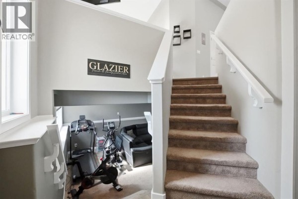 A home gym area with treadmills, an exercise bike, and a recliner chair. - 52 Castella Crescent, Red Deer