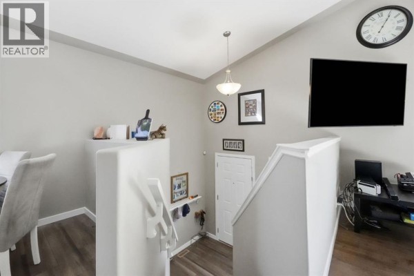 Interior entryway with stairs, a door, a clock and a television on the wall. - 52 Castella Crescent, Red Deer