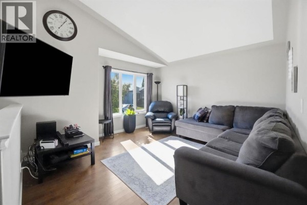 A living room with a large sectional sofa, a recliner, a television, and a window. - 52 Castella Crescent, Red Deer