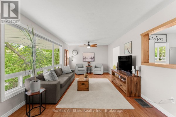 Living room with large windows, grey sectional sofa, and hardwood floors. - 52 Concession Road, Kawartha Lakes