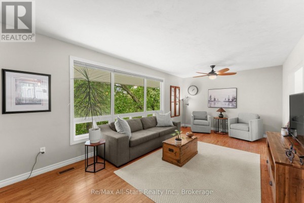 Living room with large windows, grey sectional sofa, and hardwood floors. - 52 Concession Road, Kawartha Lakes