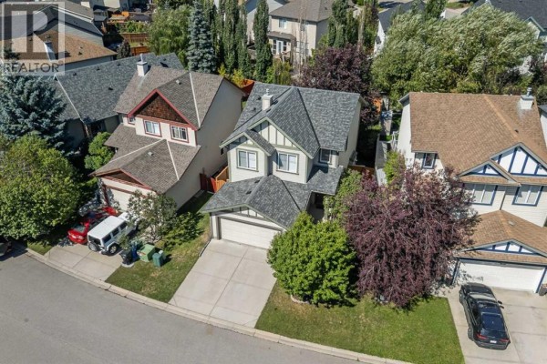 Aerial view of a suburban neighborhood with winding streets, houses, green spaces, and a pond. - 52 Copperfield Close Se, Calgary