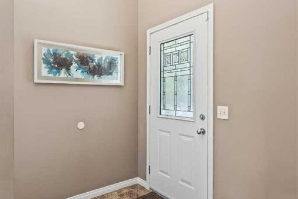 Interior view of a hallway showing a white door with a glass insert and a framed picture. - 52 Copperfield Close Se, Calgary