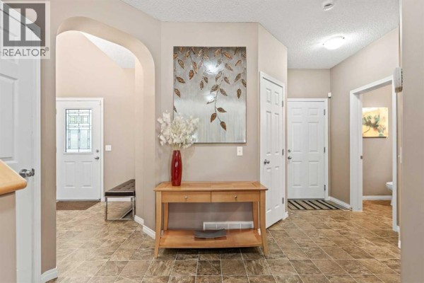 View of a home interior hallway with tiled floors, white doors, and decorative console table. - 52 Copperfield Close Se, Calgary